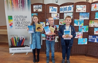 Zdjecie przedstawia nagrodzone dzieci z klasy I na tle wystawki prac konkursowych