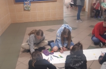 uczniowie maluja plakat na tle gazetki o autyzmie