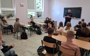 Klasa 4 i 5 siedzaca na krzeslach podczas spotkania z policjantem